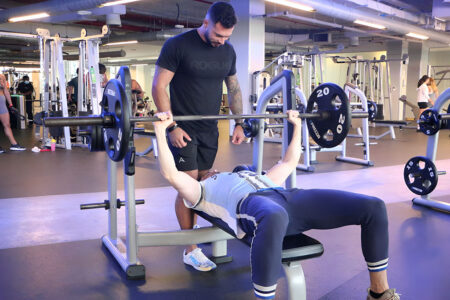 A man preparing to bench press with his personal trainer spotting him A man preparing to bench press with his personal trainer spotting him