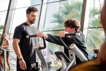 A personal trainer talking to his client while he exercises A personal trainer talking to his client while he exercises