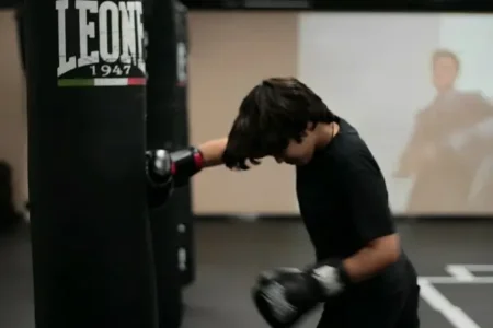 a young boy is punching a punch bag with his maximum strength at fitrepublik